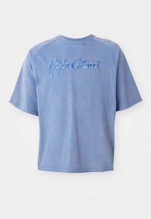 Camiseta azul de gran tamaño hecha de algodón, con un diseño de manga raglán y texto bordado con efecto de goteo.