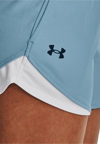 Ljusblå idrottsshorts i texturerad veckad tyg med vit kant. Har en mörk logotyp på sidan och platta sömmar för komfort.