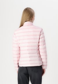 Giacca a vento rosa con trapuntatura orizzontale, colletto alto e texture liscia. Presenta una silhouette leggermente aderente e polsini elasticizzati.