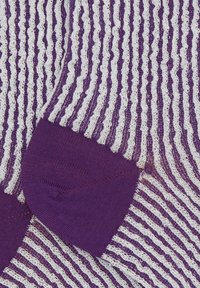 Calzini a righe viola e bianche con un motivo a maglia testurizzato, caratterizzati da un tallone viola uniforme. Il design include righe ondulate alternate.