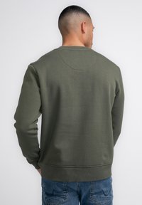 Olijfgroene sweatshirt met lange mouwen, ronde hals, ribgebreide manchetten en zoom. Gemaakt van textiel met een gladde achterzijde.