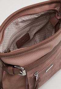 Helle rosa Handtasche mit strukturiertem Außenmaterial, Reißverschluss und gepunkteter Fütterung. Verfügt über eine zusätzliche Reißverschlusstasche und ein Logo-Tag im Inneren.