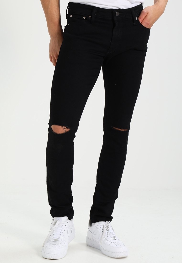 Svarta skinny jeans med rivna knän, tillverkade av denim. Kombinerat med vita sneakers. Har standardfickor och silverfärgade detaljer.