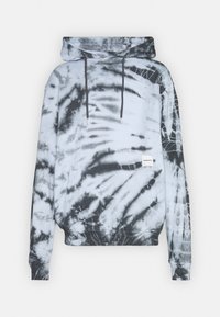 Sudadera con capucha de patrón de tinte anudado en blanco y negro, con un bolsillo canguro en la parte frontal y cuerdas de ajuste negras sobre un fondo claro.
