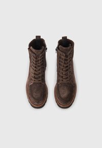 Botas de tornozelo em camurça castanha com atacadores na frente, fecho lateral, forro de lã, sola de borracha castanha e costura em contraste.