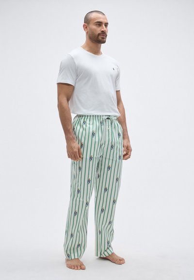 Bijela majica kratkih rukava i zelene pidžama hlače s prugama i višebojnim tiskom crtane figure, s elastičnim pojasom i vezicom.