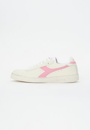 Baskets blanches à surface texturée, avec un logo latéral rose et des accents. Le design comprend des lacets blancs et une semelle en caoutchouc.