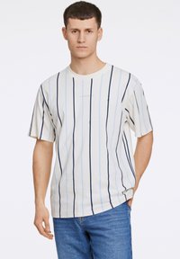 Gestreept T-shirt van lichte stof met verticale marineblauwe en lichtblauwe strepen, korte mouwen en een ronde hals. Eenvoudig ontwerp met logo-detail.