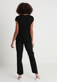 Top negro de manga corta y pantalones anchos negros, ambos de un tejido suave. El conjunto presenta un corte relajado y un diseño sencillo.