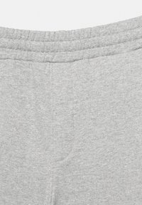 Pantaloni de trening gri cu talie elastică cu tiv reiat și material moale, texturat, cu un model discret melanj. Fără buzunare sau cusături vizibile.