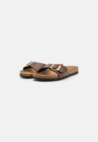 Brune skinn slip-on sandaler har en korkfotbed og en teksturert svart gummiyttersåle, supplert med en gullspenne på stroppen.