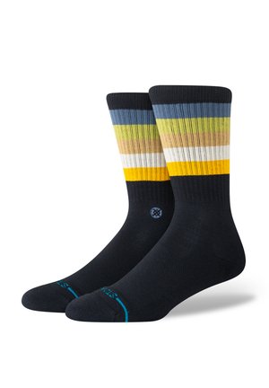 Striped socks in blue, yellow, green, and white on a dark navy background. Features ribbed texture and reinforced toe. Sporty design.