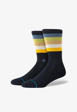 Paski skarpet w kolorach niebieskim, żółtym, zielonym i białym na ciemnonawowym tle. Charakteryzują się prążkowaną teksturą i wzmocnionym palcem. Sportowy design.