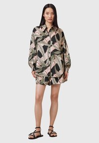 Completo con blusa a maniche corte e pantaloni corti di colore nero, caratterizzato da un motivo di foglie rosa e verdi. Realizzato in un tessuto leggero, con una vestibilità comoda.