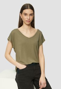 Olijfgroene, korte mouwen t-shirt met een V-hals en een relaxed fit. Zachte textuur, gecombineerd met zwarte broek. Eenvoudig ontwerp zonder patronen of accenten.