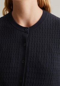 Granatowy sweter kardigan z dzianiny, z teksturowanym wzorem, okrągłym dekoltem i zapięciem na guziki z przodu. Miękka tkanina z prążkowanym wykończeniem.