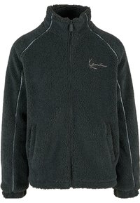 Black fleece jacket with a zip front, high collar, and two side pockets. Features textured fabric and contrasting white piping accents.
