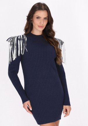 Marineblå strikket sweaterkjole med lange ærmer, der har sølvfringe detaljer på skuldrene. Blødt materiale, tætsiddende design, knælang længde.