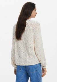 Maglione lavorato a maglia in crema con macrofibre colorate, caratterizzato da un fit morbido, polsini e orlo a costine, e un collo rotondo. Tessuto leggero.