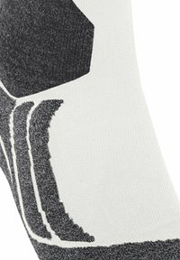 Calzino atletico bianco e nero con una finitura testurizzata, caratterizzato da un motivo esagonale e strisce curve lungo il lato.