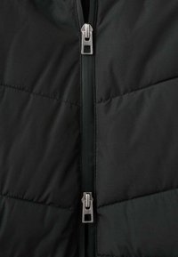 Czarna pikowana kurtka z centralnym zamkiem błyskawicznym z metalowym suwakiem, prostokątnym wzorem pikowania i gładką fakturą na całej powierzchni.