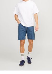 White cotton T-shirt, blue denim shorts, white socks with green stripes, and navy sneakers. Comfortable casual outfit with relaxed fit.
