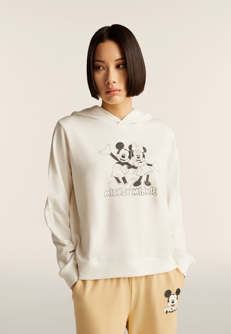 Felpa bianca con cappuccio, caratterizzata da una grafica nera di Topolino e Minni. Tessuto morbido con vestibilità comoda e una tasca marsupio.