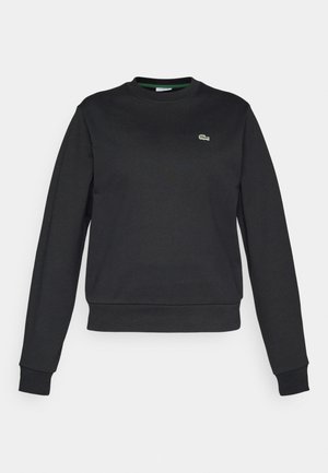 Črna dolgoročna majica s krožnim izrezom, z majhnim zeleni in belim krokodilom na levem prsnem delu, rebrasti manšeti in pasom.