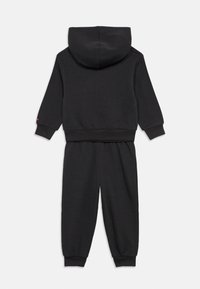 Μαύρο σετ φούτερ και φόρμας από απαλό ύφασμα. Διαθέτει κουκούλα, ριχτές μανσέτες και χαλαρή γραμμή. Απλός σχεδιασμός χωρίς σχέδια.