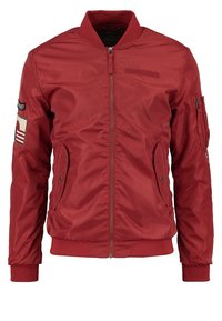 Czerwona kurtka bomberka, gładki nylonowy materiał, prążkowany kołnierz i mankiety, zamek błyskawiczny, dwie boczne kieszenie oraz naszywka na lewym rękawie.