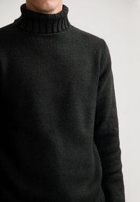 Schwarzer Rollkragenpullover aus strukturiertem Strickstoff, mit einem geribten Kragen und eng anliegenden Ärmeln. Keine Muster oder bemerkbaren Akzente sichtbar.