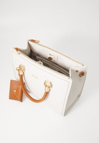 Borsa a tracolla bianca in pelle con accenti beige, hardware dorato e tracolla color tan. Presenta una chiusura con zip e un piccolo portacarte abbinato.