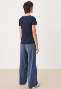 Marine t-shirt met korte mouwen, aansluitend ontwerp. Gecombineerd met wijde blauwe broek, soepel van textuur, met een ontspannen silhouet.
