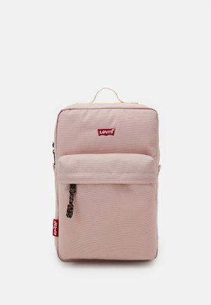 Różowy plecak Levi's z przednią kieszenią na zamek, górnym uchwytem i czerwonym logo Levi’s na przodzie i bocznej metce.