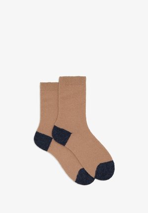 Knit socks, beige body with dark blue heel and toe accents, ribbed cuff at the top, soft texture, standard crew length.