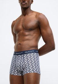 Marineblaue Boxer-Pants mit weißem Muster aus ineinandergreifendem Logo, elastischem Bund mit "GANT"-Schriftzug, figurbetonter Schnittform, glatter Stofftextur.