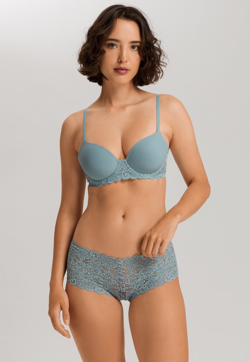 Set di reggiseno e mutandine in morbido tessuto blu. Il reggiseno presenta coppe lisce con bordi in pizzo; le mutandine hanno un design floreale in pizzo e bordi scallop.