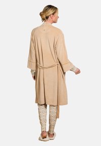 Beige suede robe with a tie waist, long sleeves, and a soft texture, paired with patterned, fitted pants in cream and multicolor designs.