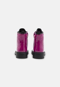 Botas de tobillo de charol rosa con suela de goma negra, que presentan un diseño de estrellas en el lado exterior y un cierre de cremallera para un acceso fácil.