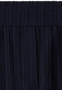 Tissu bleu marine foncé avec des rayures verticales texturées et une ceinture élastique froncée avec des détails de couture.