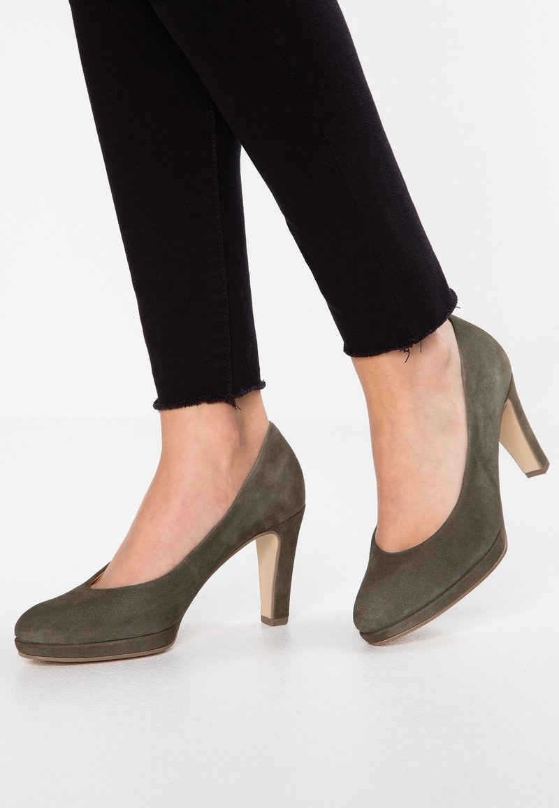 Chaussures à talons hauts en daim vert olive avec bouts arrondis et plateforme. Les talons sont transparents avec une base de couleur claire.
