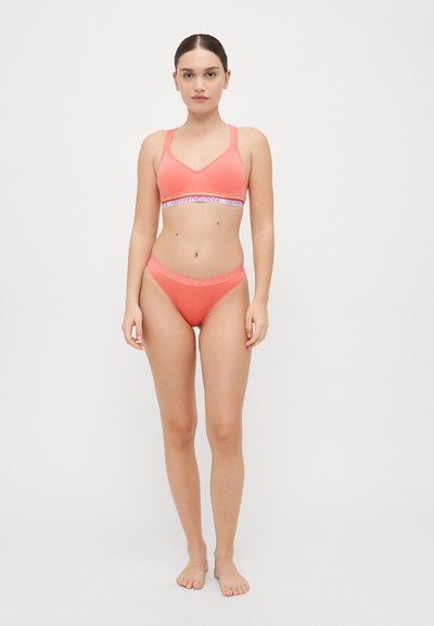 Coral sports bra and matching bikini with a wide elastic band featuring text. Smooth finish and fitted design, minimalistic style.