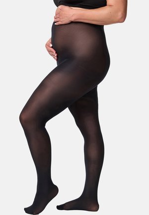 Schwangere Person trägt durchsichtige schwarze Schwangerschaftsstrumpfhose, steht mit einem leicht angewinkelten Bein und legt die Hände auf den Bauch.