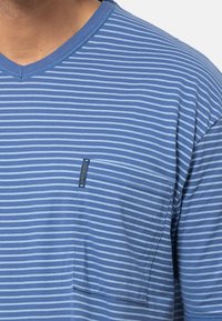 T-shirt a righe blu e azzurro chiaro con scollatura a V, caratterizzato da una piccola tasca sul petto e un'etichetta del marchio sul bordo della tasca. Tessuto morbido.
