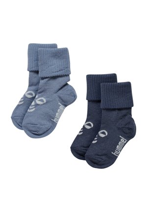 Twee paar baby sokken, één lichtblauw en één donkerblauw, beide geribbeld met omgeslagen boorden en witte tekst op de zolen.