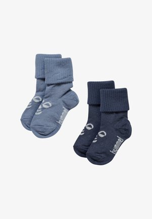 Twee paar baby sokken, één lichtblauw en één donkerblauw, beide geribbeld met omgeslagen boorden en witte tekst op de zolen.