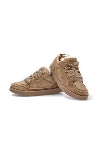 Zapatillas de deporte en tono marrón, fabricadas en ante y malla, con cordones gruesos y texturizados y un collar acolchado. La suela es de goma, con un diseño plano y la puntera redondeada.