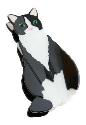 Schwarz-weißer haarclip in Katzenform mit grünen Augen, rosa Nase und glänzender Oberfläche, leicht seitlich betrachtet.