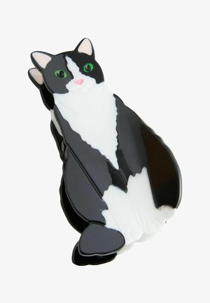 Schwarz-weißer haarclip in Katzenform mit grünen Augen, rosa Nase und glänzender Oberfläche, leicht seitlich betrachtet.