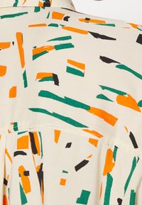 Short-sleeve shirt with a cream background featuring an abstract pattern in green, orange, and black. Smooth fabric, standard collar.